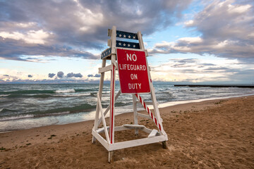 Lifeguard stand with no lifeguard on duty as the sun sets on lake Michigan.  Lighthouse beach,...