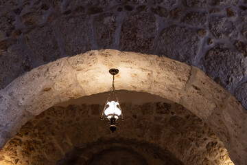 A lamp hanging from an arch of an ancient monastery