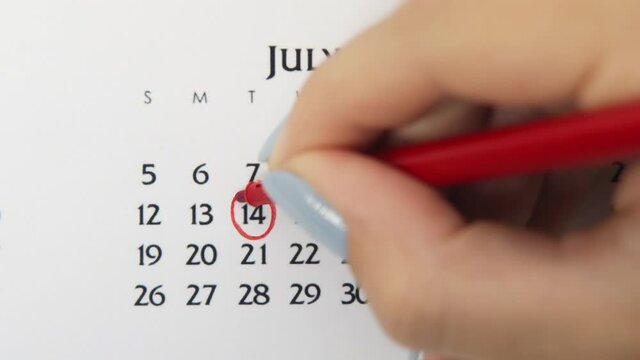Female hand circle day in calendar date with a red marker. Business Basics Wall Calendar Planner and Organizer. July 14th