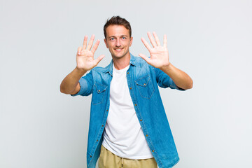 young handsome man smiling and looking friendly, showing number nine or ninth with hand forward,...