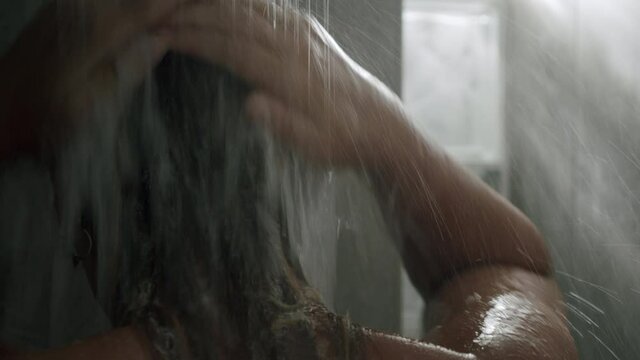 A close up of a womans nape in a shower - she is washing her hair with her hands