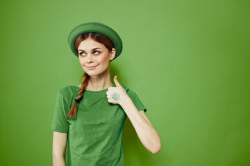 Happy woman with shamrock on St. Patrick's Day in green clothes and a hat on her head gesturing with her hands