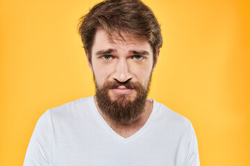 Fototapeta premium Man with emotional expression white t-shirt close-up studio yellow background