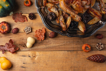 Round dish with baked turkey, potato and mushrooms on wooden background with autumn harvest. Festive dinner. Thanksgiving day concept. Traditional recipe. View from above. Flat lay.