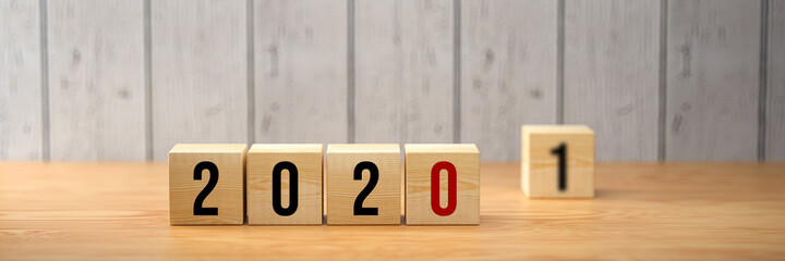 cubes showing the number 2020 and another one with a 1 standing by on wooden background