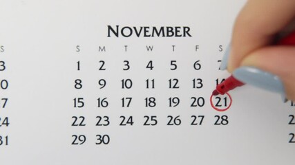 Female hand circle day in calendar date with a red marker. Business Basics Wall Calendar Planner and Organizer. November 21th