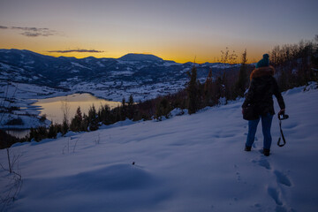 Fototapeta na wymiar Photographers photographing winter lake mountain scene in sunset, alone in wilderness