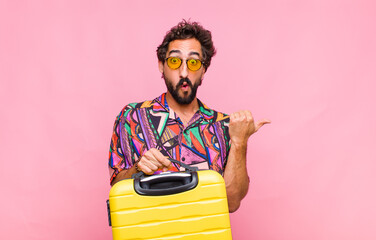 young bearded man looking astonished in disbelief, pointing at object on the side and saying wow,...