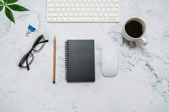 Office desk table with blank notebook, computer keyboard and other office supplies. Top view, flat design.