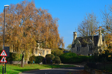 Autumn street with an old English house, next to a birch tree.
