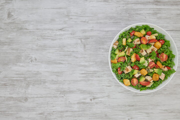Grilled Chicken Avocado Salad with Kale, Grilled Chicken, Avocado, Grape Tomatoes, Croutons, Pepitas, and Parmesan.