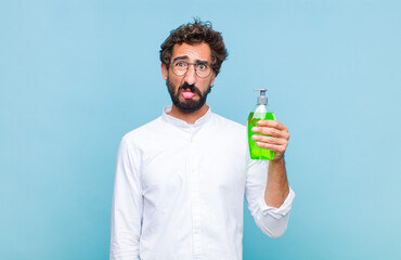 young bearded man feeling disgusted and irritated, sticking tongue out, disliking something nasty...
