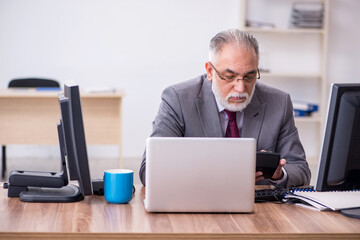 Old male boss sitting at desktop in the office