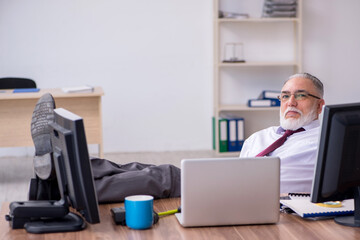 Old male boss sitting at desktop in the office