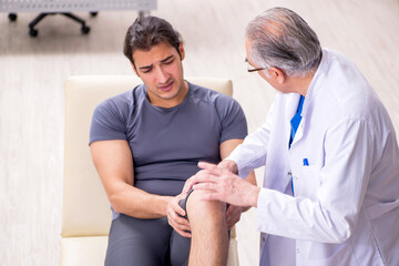 Young male patient visiting old doctor traumatologist