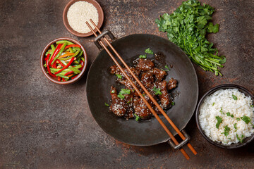 Chicken teriyaki with rice and vegetables on brown background.