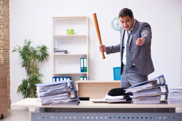 Young employee angry with excessive work holding baseball bat