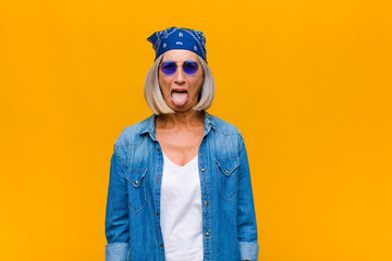 middle age woman with cheerful, carefree, rebellious attitude, joking and sticking tongue out,...