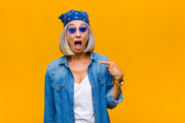 middle age woman looking shocked and surprised with mouth wide open, pointing to self