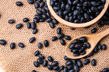 Black beans in wooden spoon and a bowl on on a wooden table top view, Close-up and macro shot, Organic food from nature concept.
