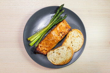 A plate of sourdough bread, salmon, and asparagus.