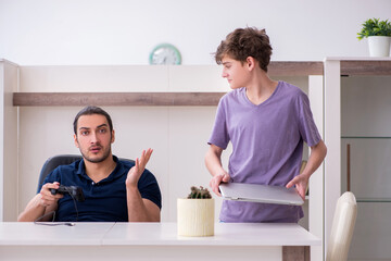 Young father and schoolboy playing computer games at home