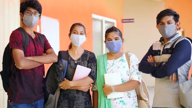 Group of young college students with medical mask coming and standing confidently in front of camera with arms crossed - concept of college reopen after coronavirus or covid-19 pandemic