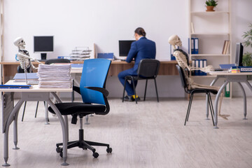 Young male employee with skeletons in the office