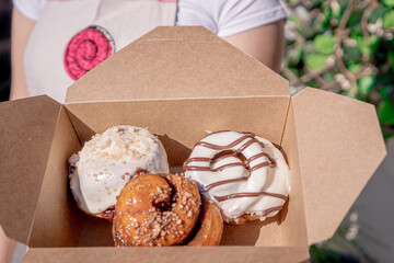 Delicious cinnamon rolls glazed and decorated inside a box held by a woman.
