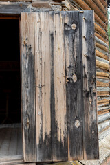 Texture of vintage wooden open door surface colored with brown paint made with weathered boards as background extreme close view. Traditional architectural style