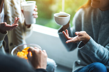 Closeup image of friends talking, drinking and eating potato chips together