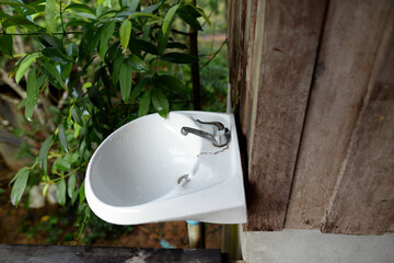 A white ceramic washbasin is attached to an old wooden wall