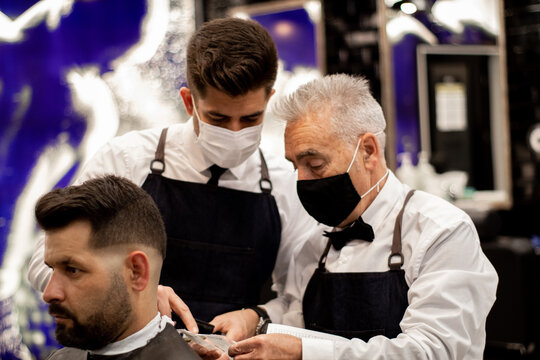 A Young Barber Talks To His Co-worker While Looking At A Bill