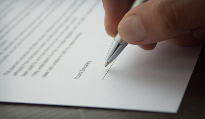 A hand signing a letter. Hand holding a pen.
