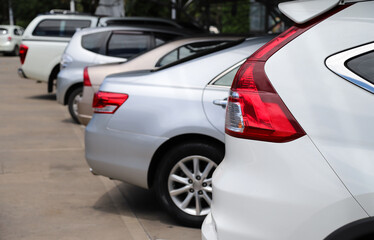 Closeup of rear side of white car and other cars parking in parking area.