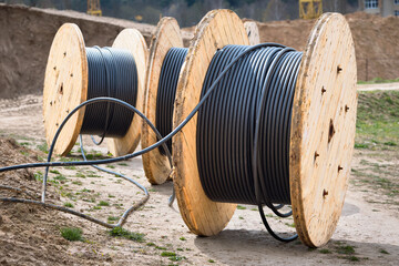 Concept of electricity supply for construction projects. Several wooden coils with power cable laid...