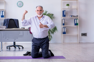 Aged male employee doing physical exercises during break