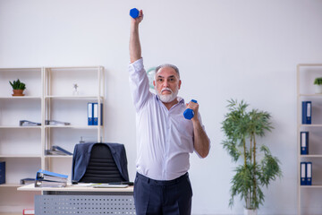 Fototapeta na wymiar Aged male employee doing physical exercises during break