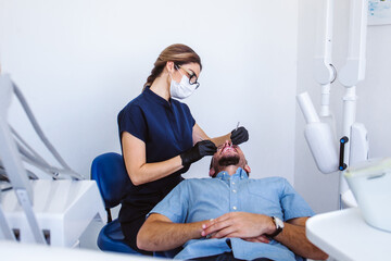 female latin dentist performing inspection to male patient in Mexico