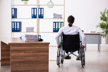 Young male employee after accident in wheel-chair at workplace