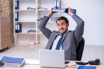 Young male employee unhappy with excessive work in the office