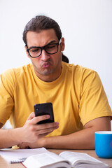 Young male student holding mobile phone during exam preparation