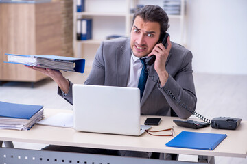 Naklejka premium Young male employee unhappy with excessive work in the office