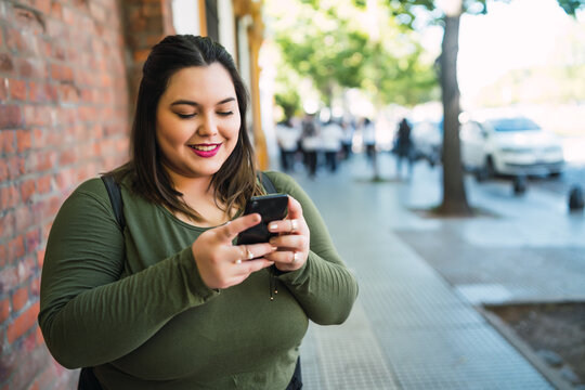 Young plus size woman using her mobile phone.