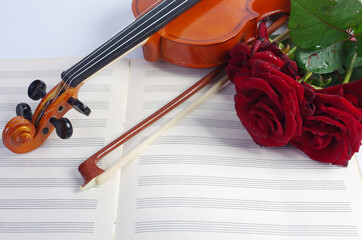Fototapeta premium Violin with a bow, music book and three red roses.