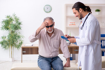 Old blind man visiting young male doctor