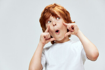 Grimacing red-haired boy with open mouth holds his hands near his face surprised look © SHOTPRIME STUDIO