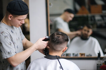 Handsome man getting haircut by barber while sitting in chair at barbershop.