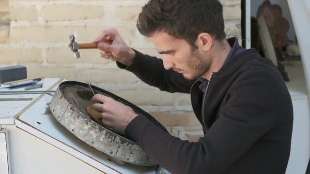 Bukhara master engraves patterns on a tray. Slow motion