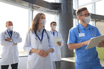 Group of medicine doctors in preventive masks talking during conference.